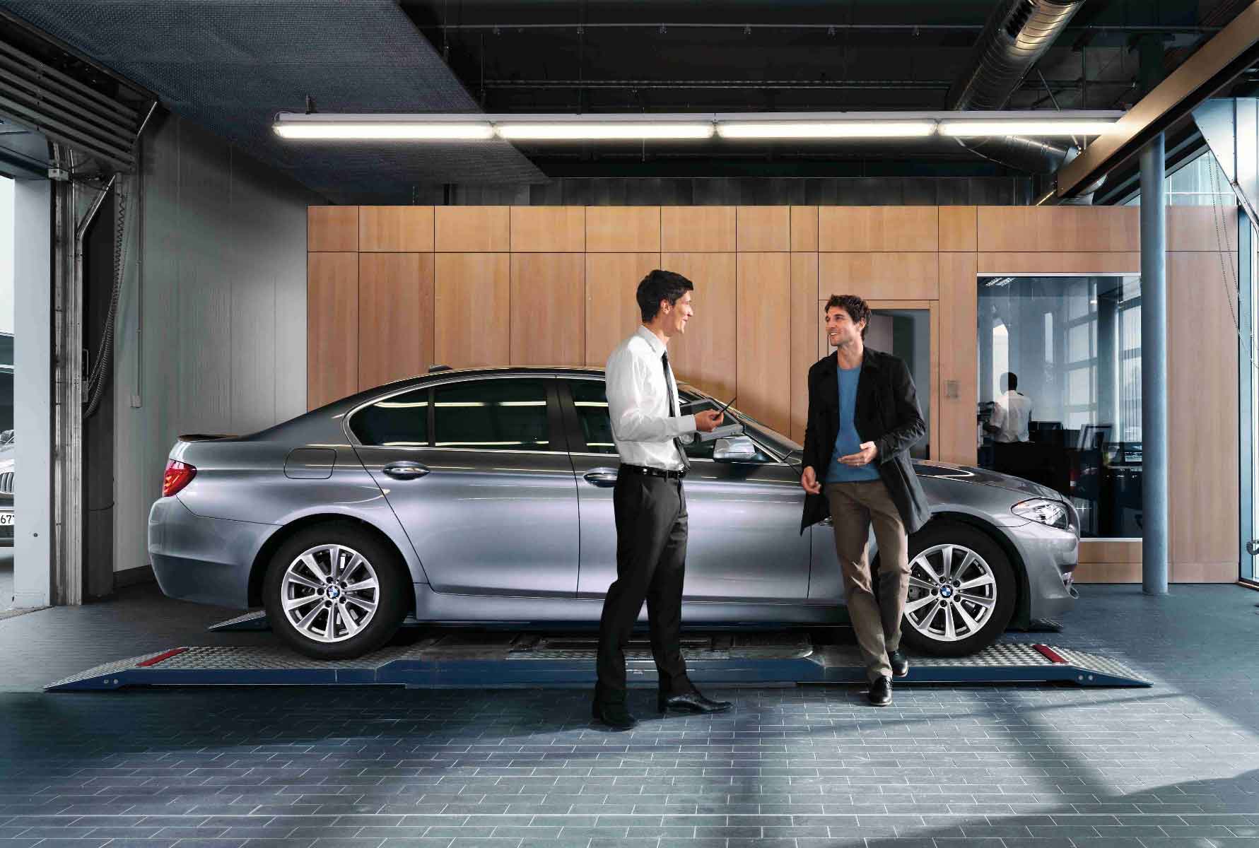 Verkäufer redet mit Kunden und zeigt das BMW Abo.